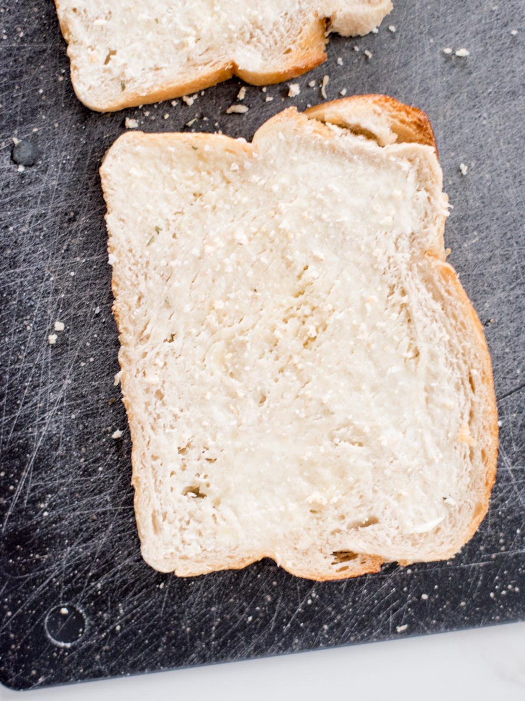 slice of buttered bread on a cutting board sprinkled with garlic salt