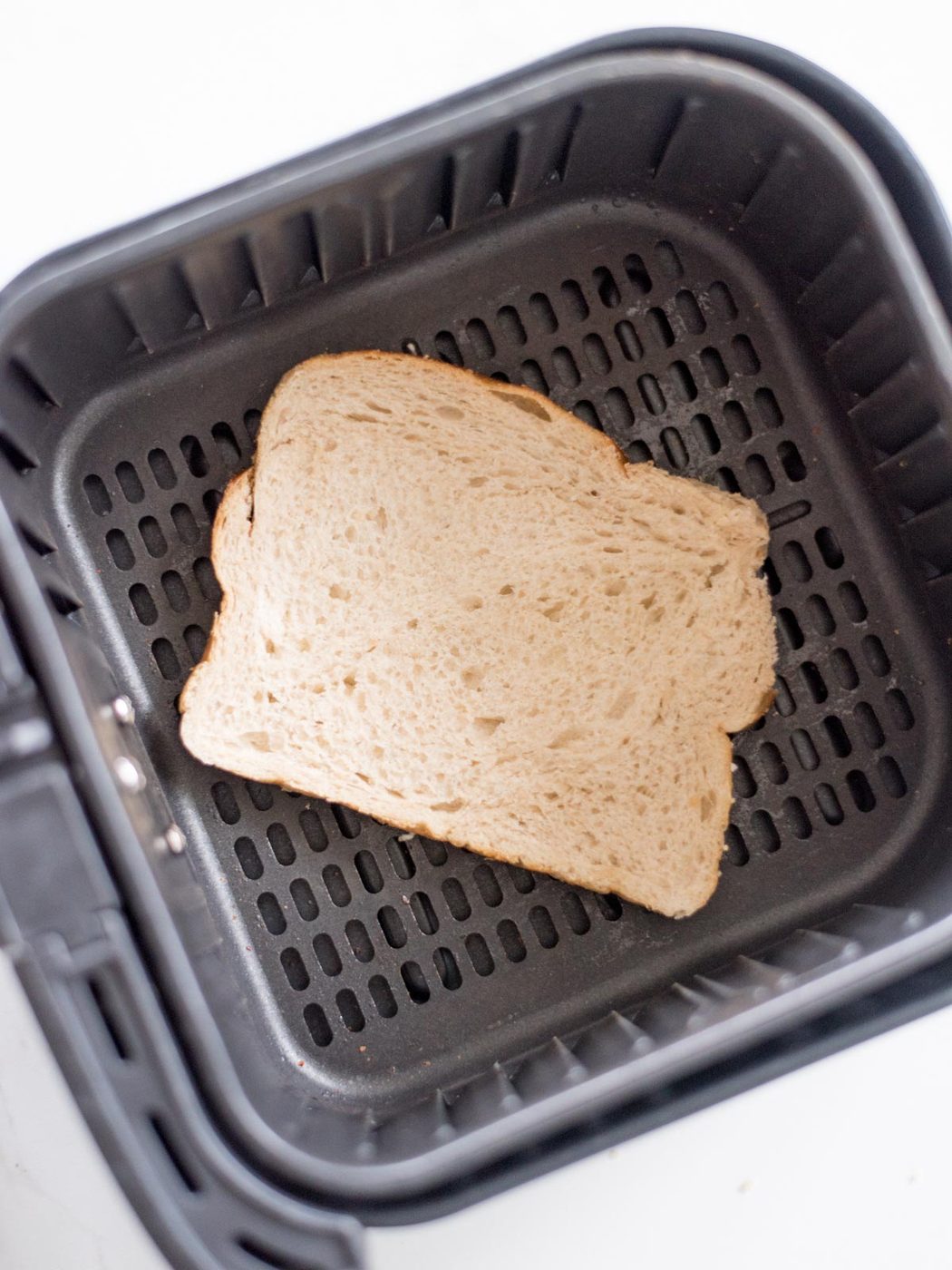 slice of buttered bread, butter side down in an air fryer basket