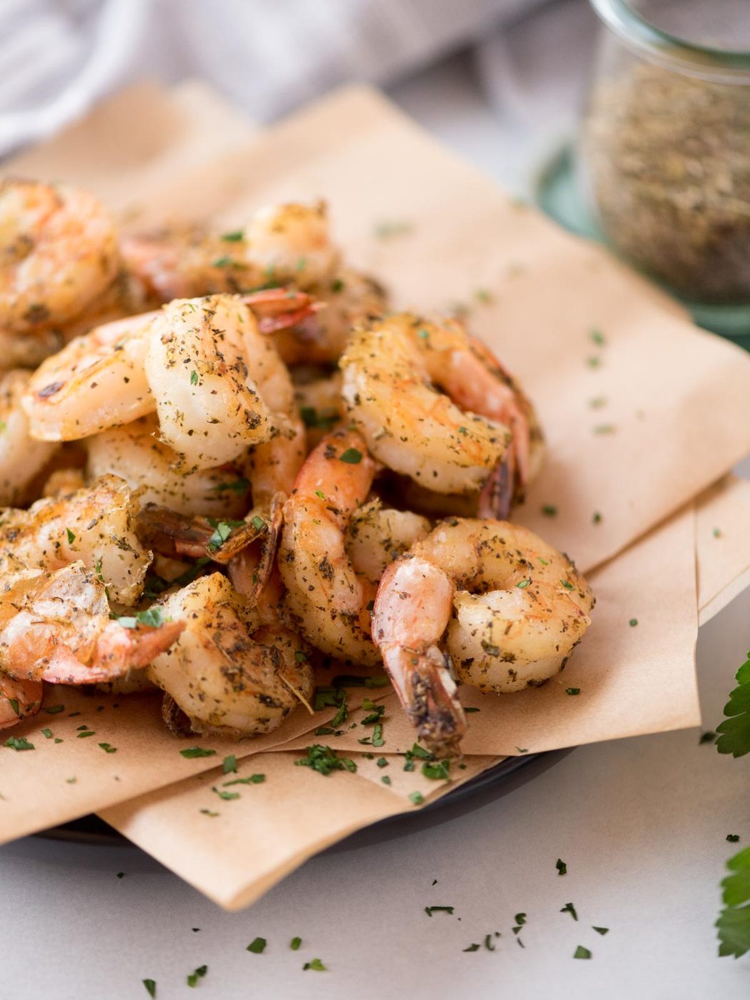 Air fryer frozen seasoned shrimp served on parchment paper covered plate.