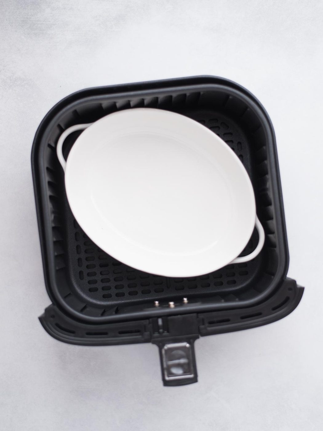 Empty baking dish sitting in the air fryer bucket.