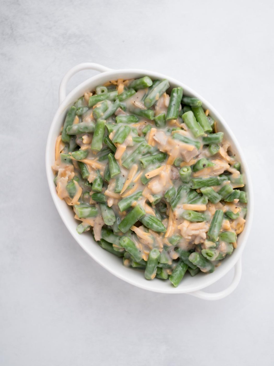 White baking dish filled with uncooked green bean casserole.