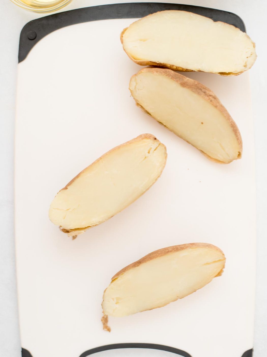 2 russet potatos cut in half and laying on a cutting board, ready to prepare for potato skins.