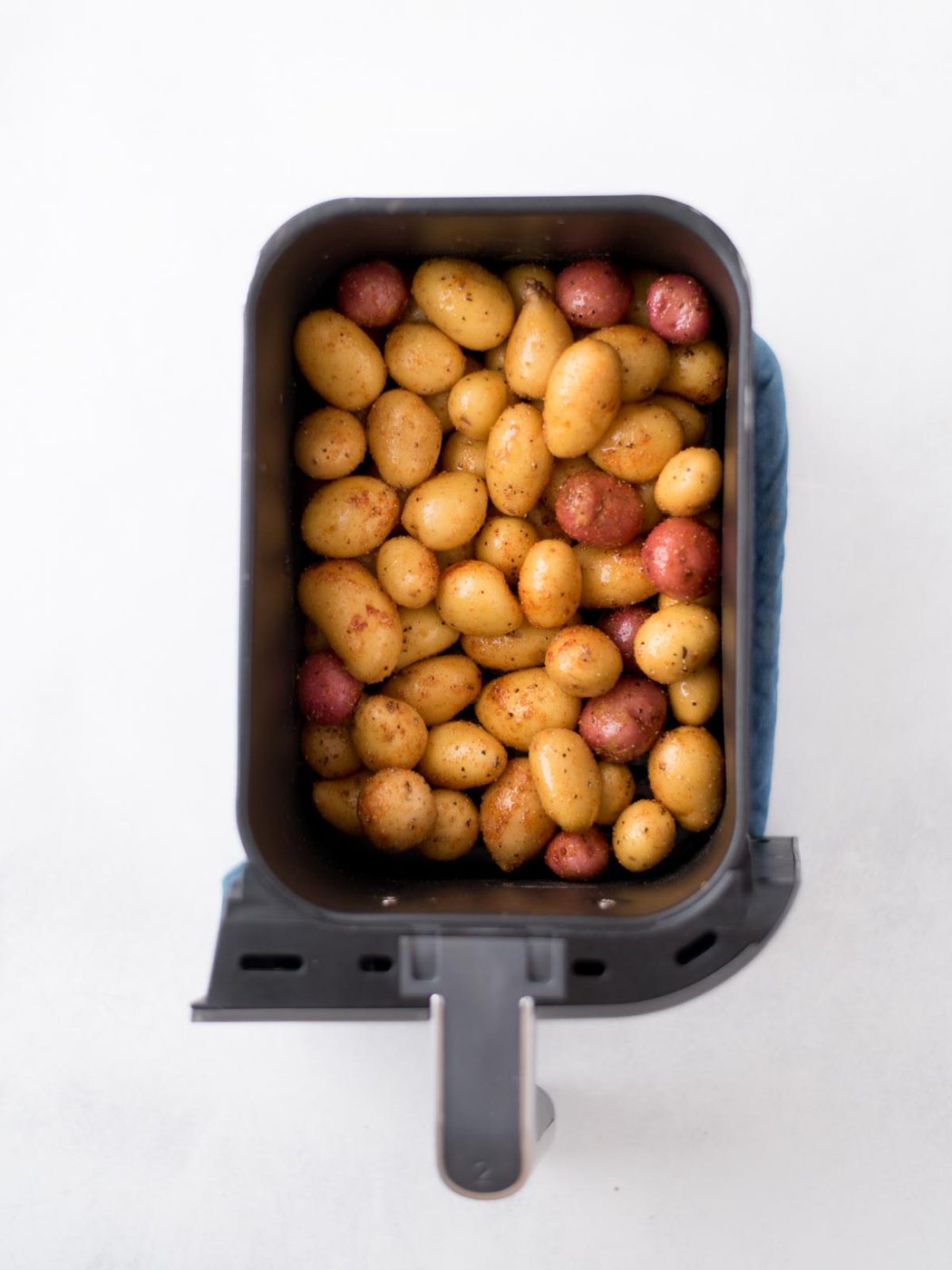 seasoned uncooked baby potatoes in an air fryer basket