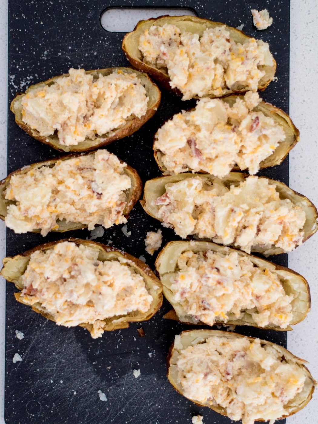Twice baked potatoes sitting on a cutting board with the potato mixture added back in.