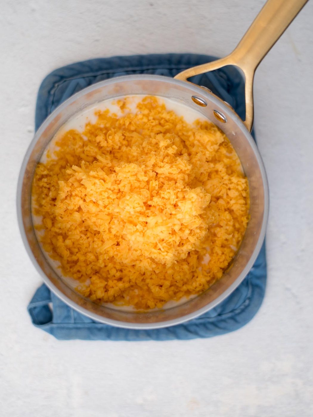 Shredded cheese added to a saucepan.