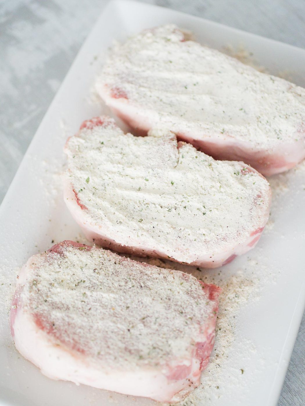 pork chops covered in seasoning on a white plate