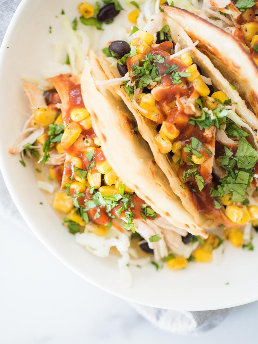 a white shallow bowl with bbq chicken tacos with toppings