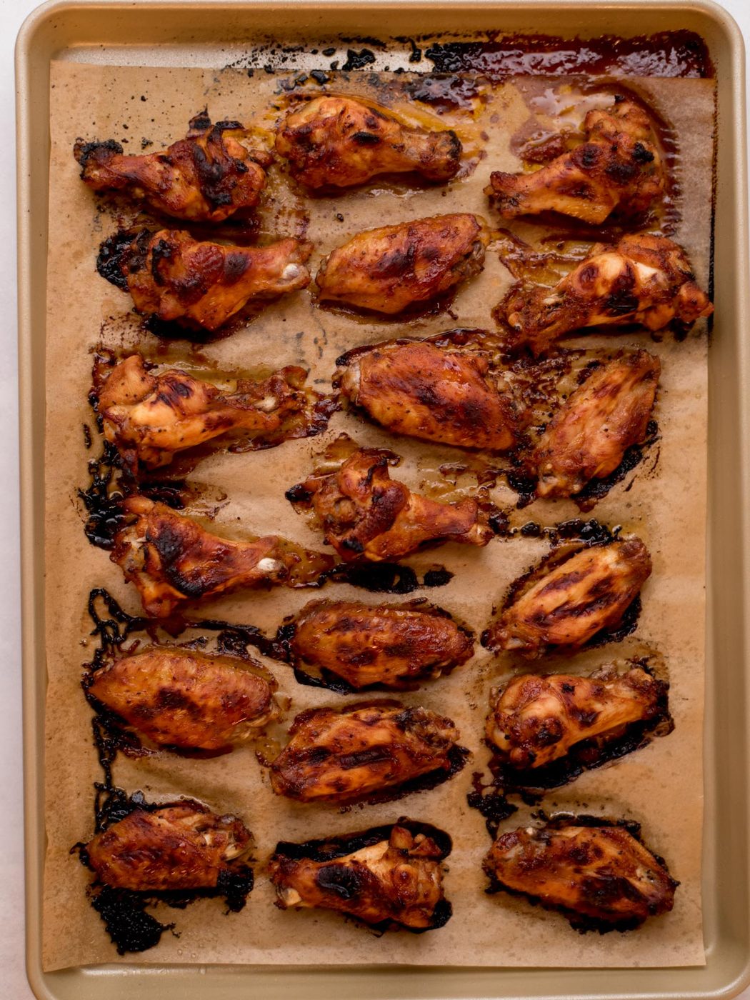 cooked bbq chicken wings on a parchment lined baking sheet