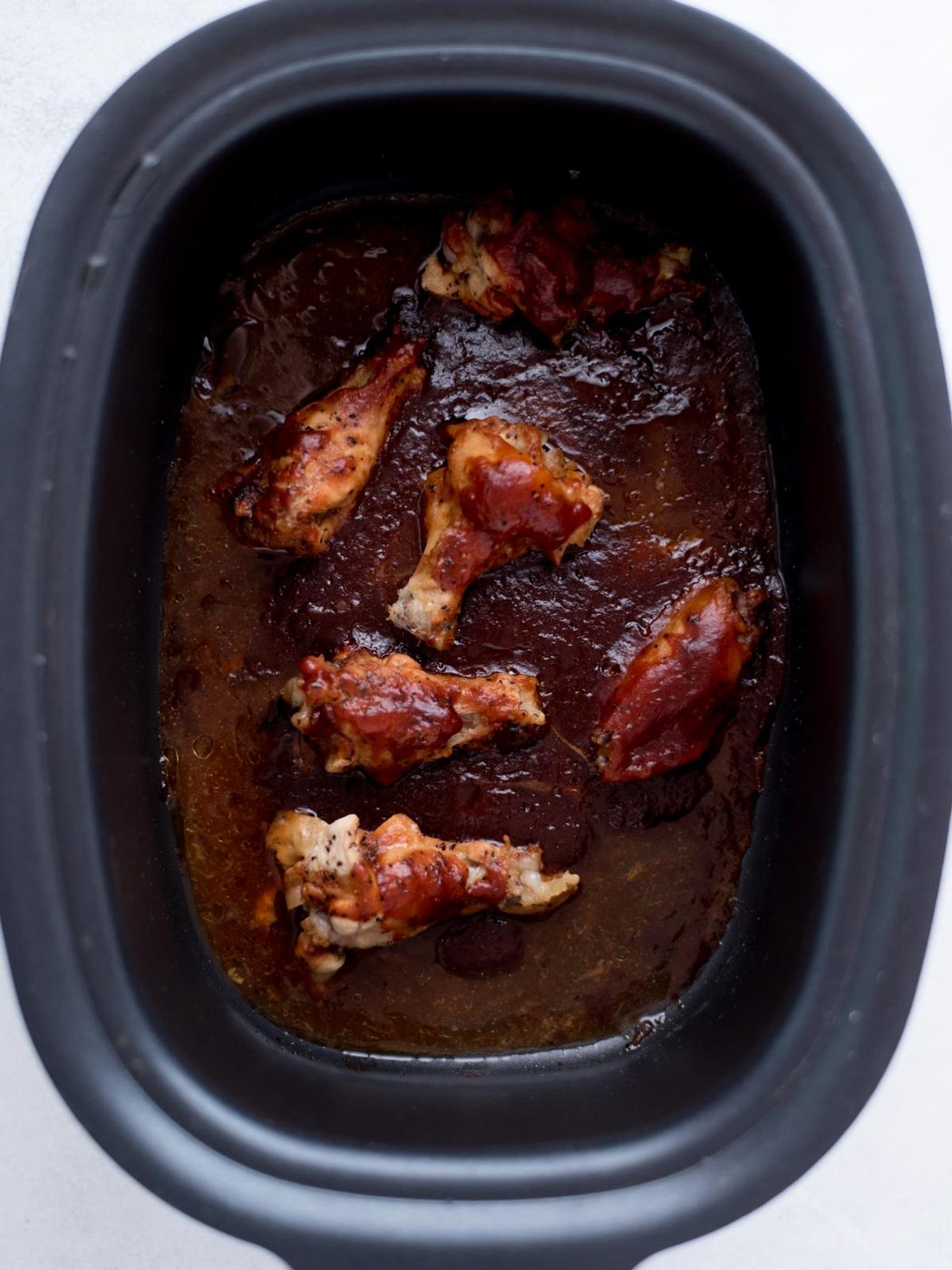Cooked bbq chicken wings inside a crockpot.