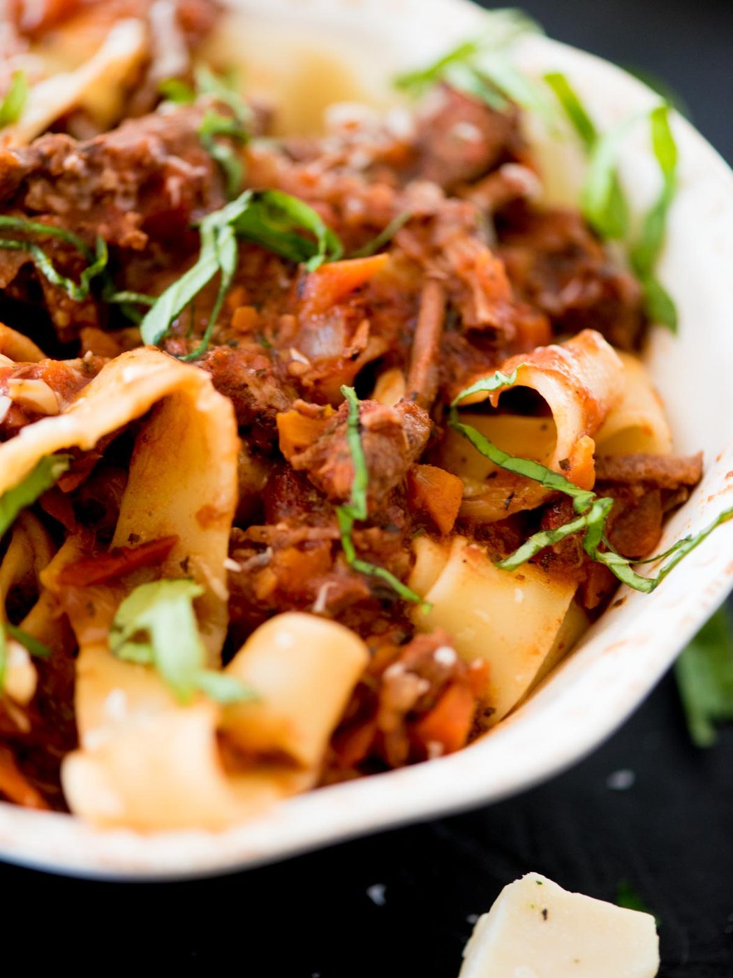 beef ragu over pasta topped with basil and parmesan
