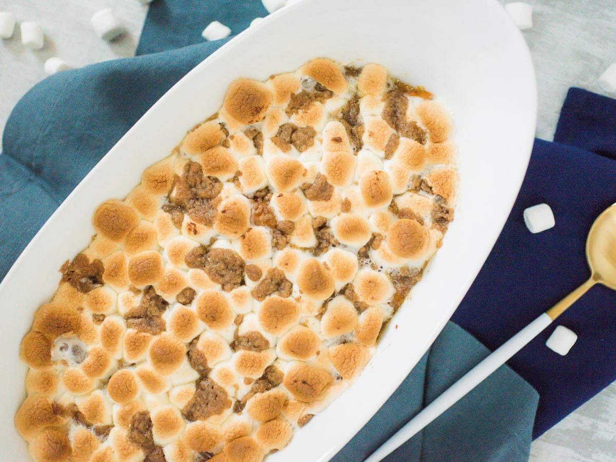 sweet potato casserole in a white baking dish on blue cloth
