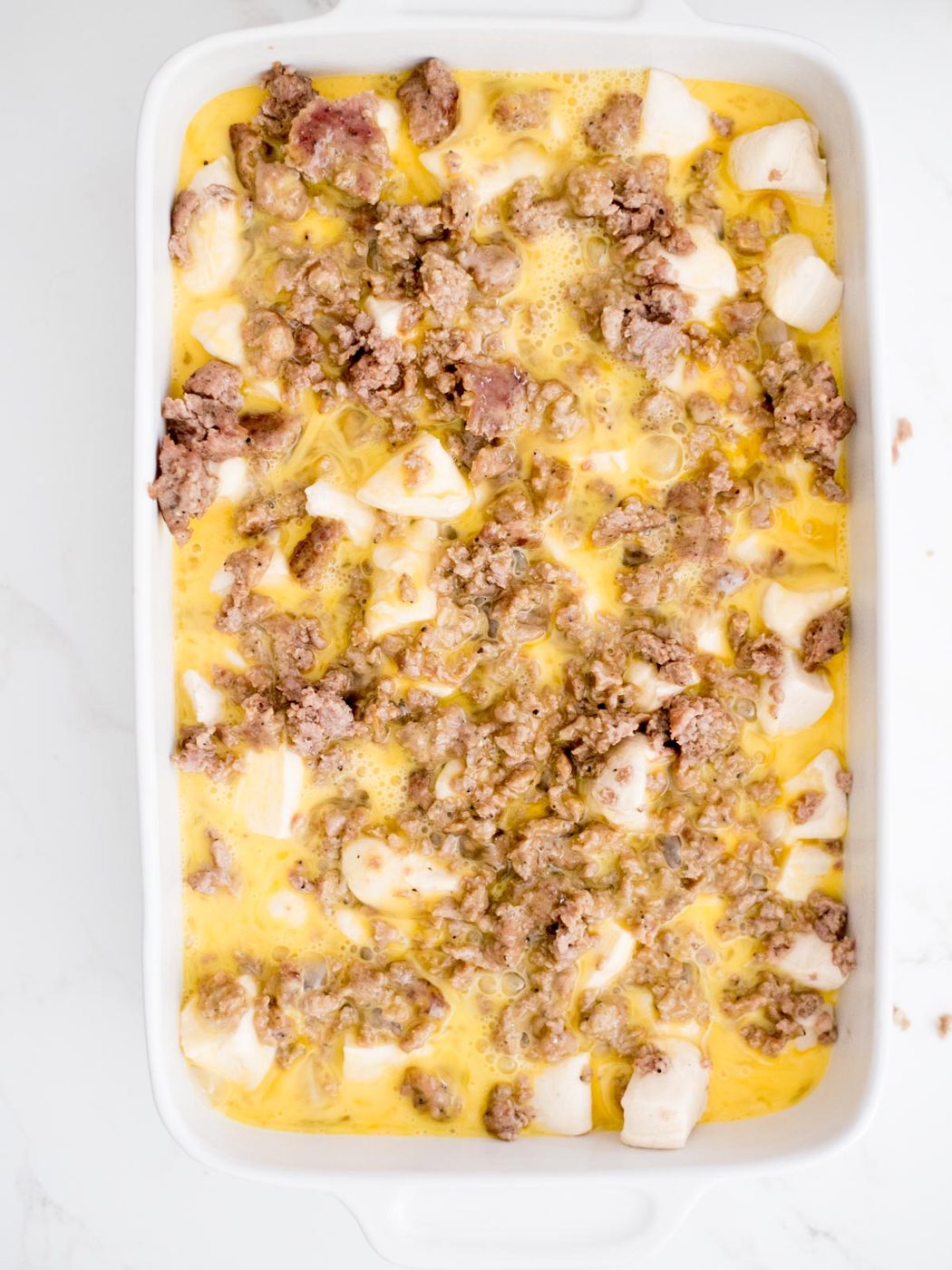 eggs added to casserole dish with biscuits and sausage