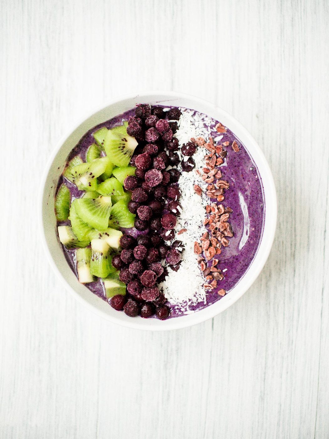 blueberry banana smoothie bowl in a white bowl with toppings