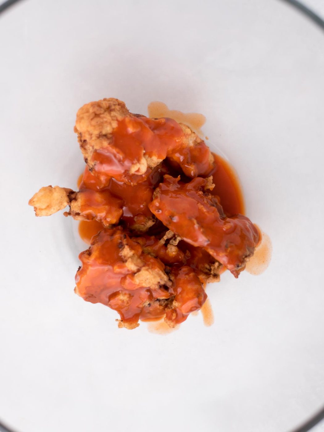 boneless wings coated in sauce in a mixing bowl