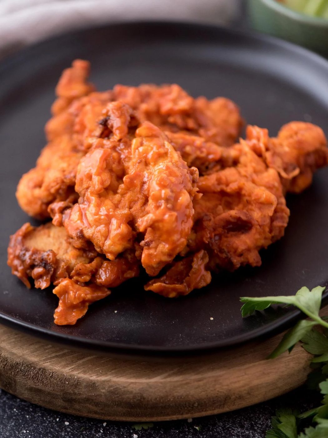 boneless wings coated in sauce on a black plate garnished with parsley