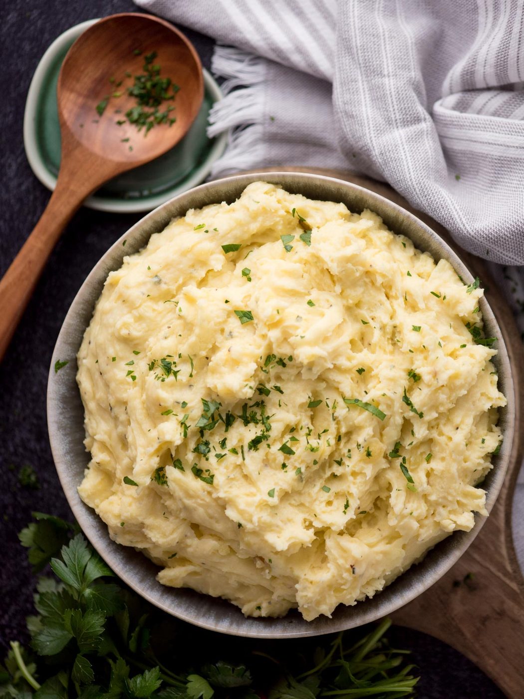 Serving bowl of boursin mashed potatoes next to a wooden spoon rest.