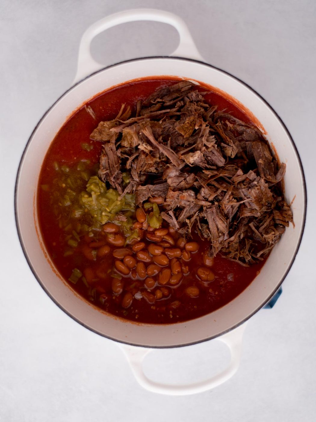 ingredients for brisket chili added into a dutch oven before they've been mixed together