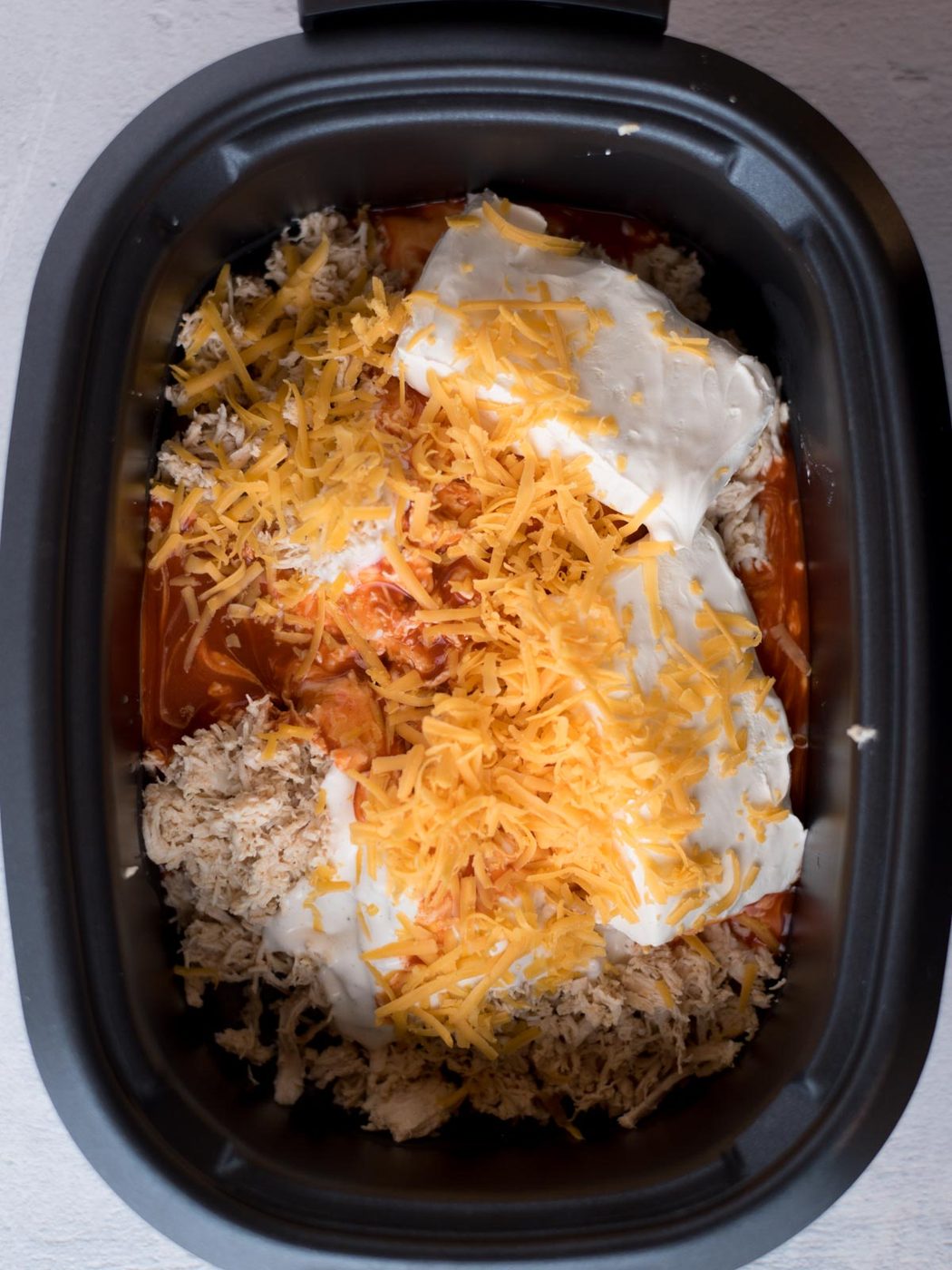 ingredients for crockpot buffalo chicken dip in a slow cooker