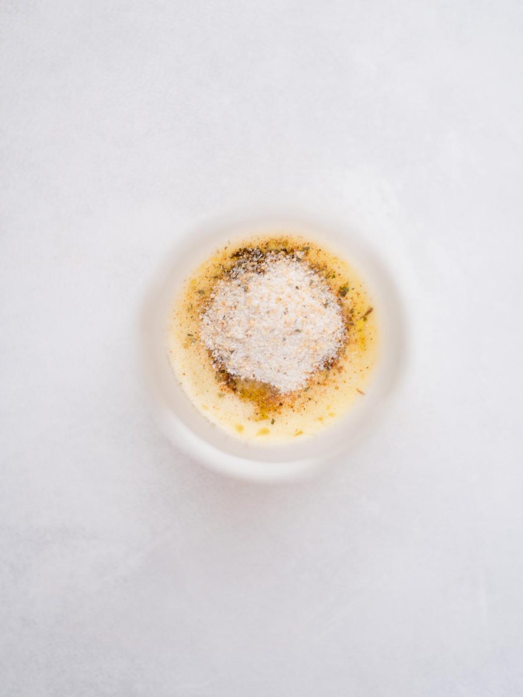 Measured seasonings added to melted butter in a small bowl for buffalo chicken sliders.