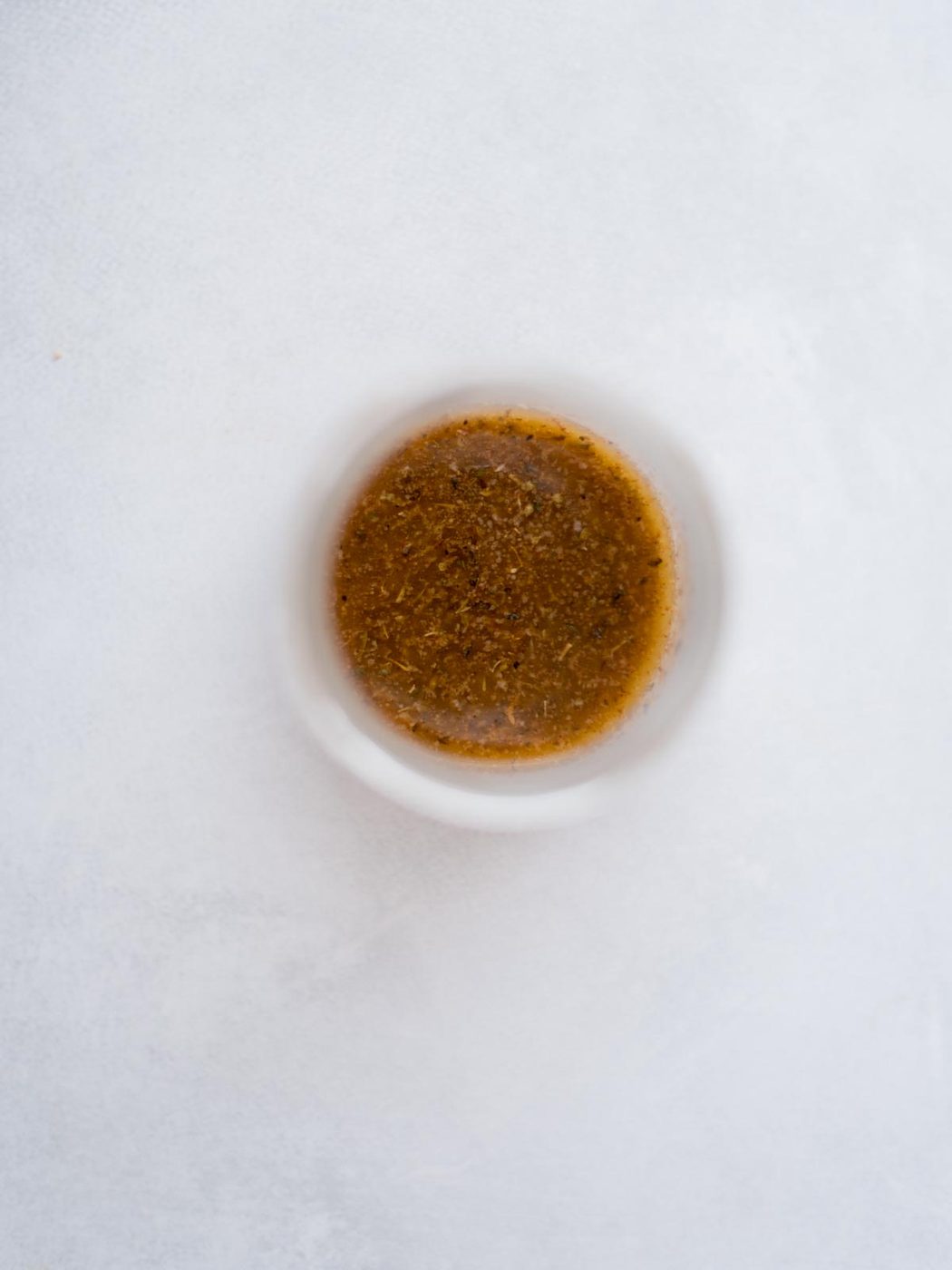 Seasoned melted butter in a small bowl for buffalo chicken sliders.
