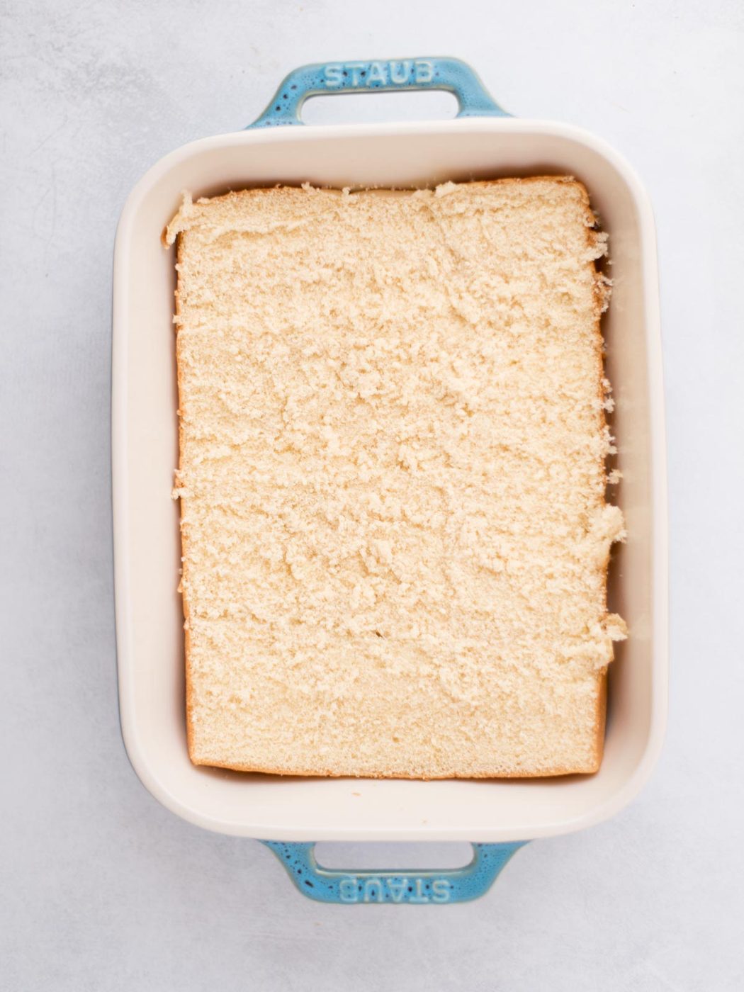 Bottom half of sliders buns placed in a baking dish.