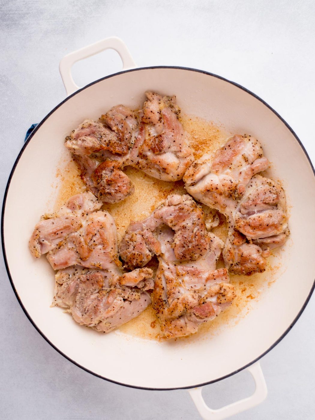 buffalo chicken thighs searing in a skillet