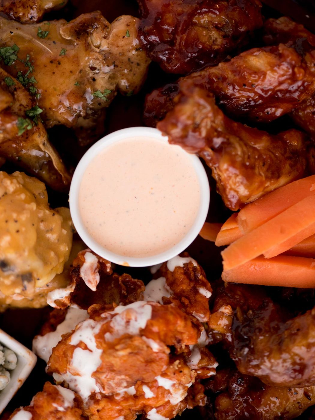 buffalo ranch sauce in a container surrounded by buffalo wings and carrot sticks