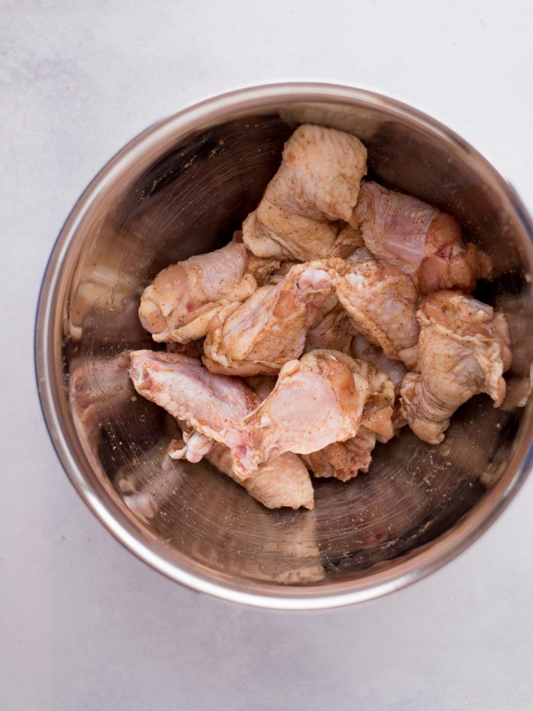 Bowl of raw chicken wings with the cajun seasoning.