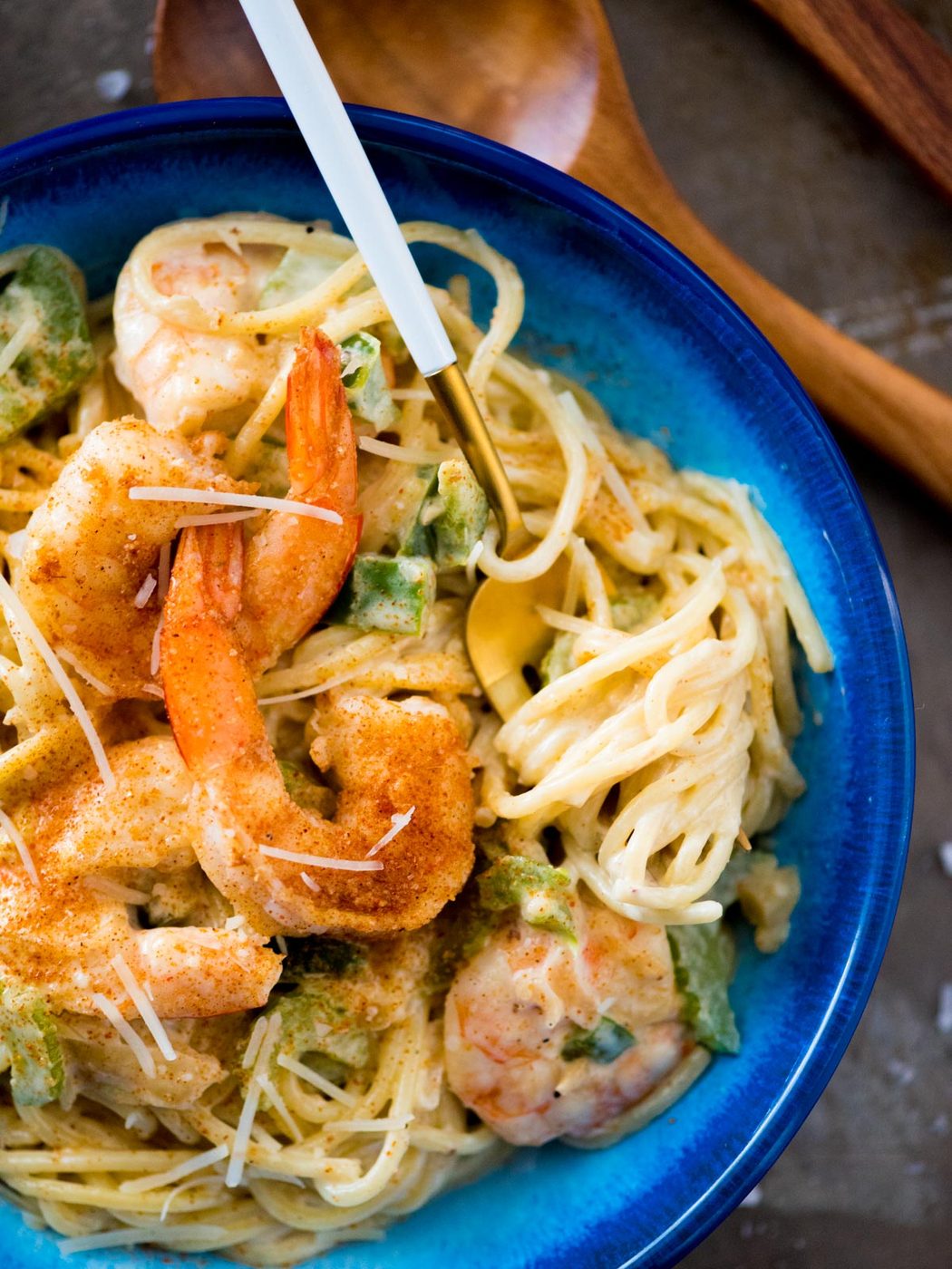 cajun shrimp alfredo in a blue bowl topped with parmesan