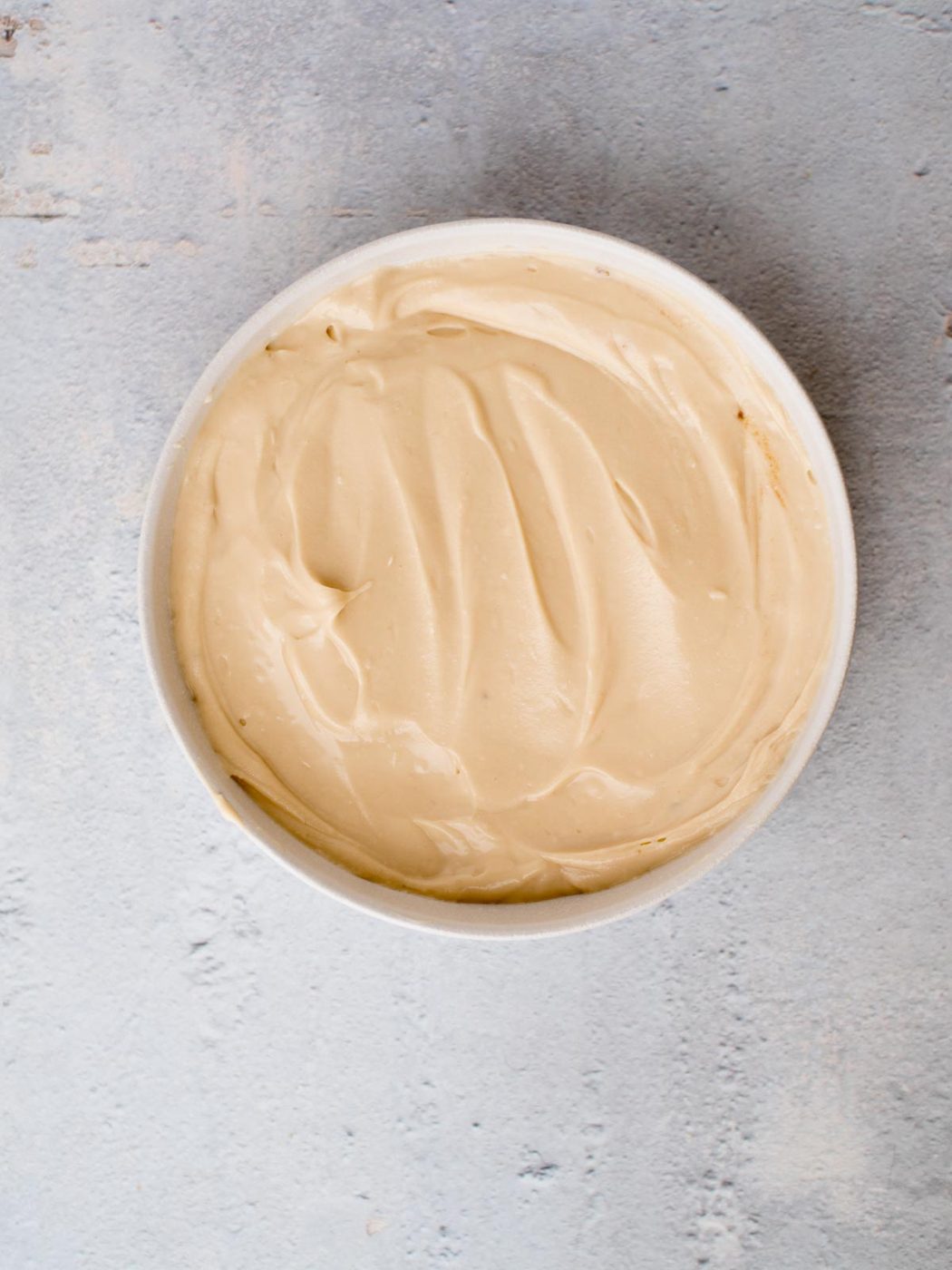 cream cheese layer of caramel apple dip in a white dish