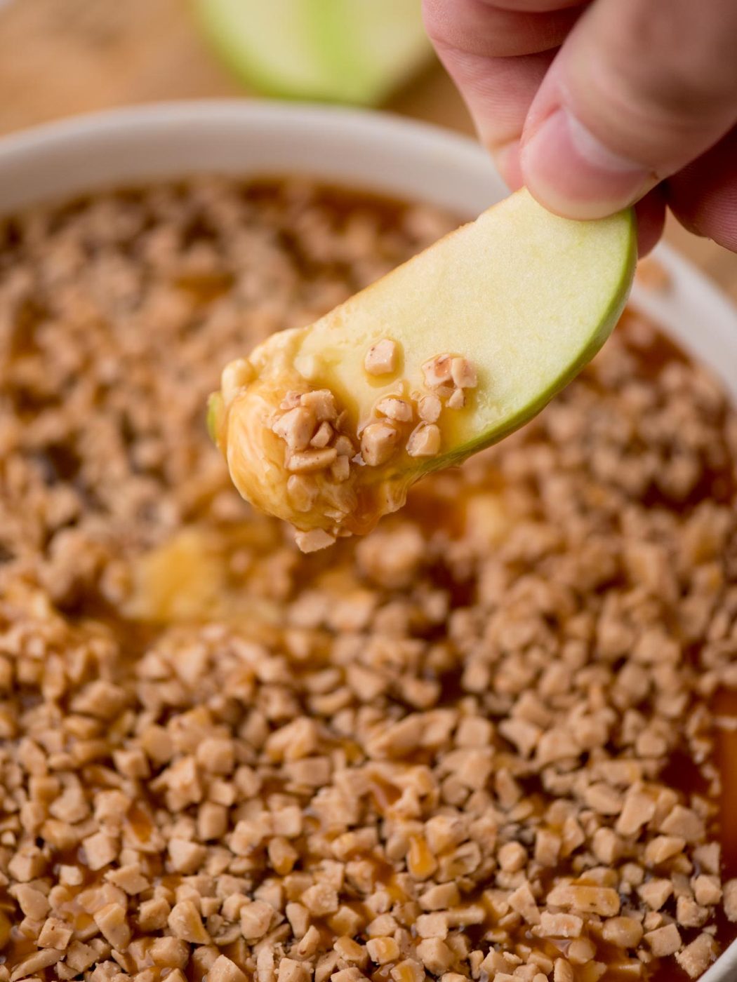 A slice of green apple covered in caramel apple dip.