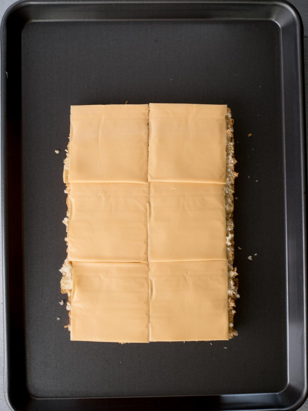 american cheese slices on top of the bottom half of hawaiian buns