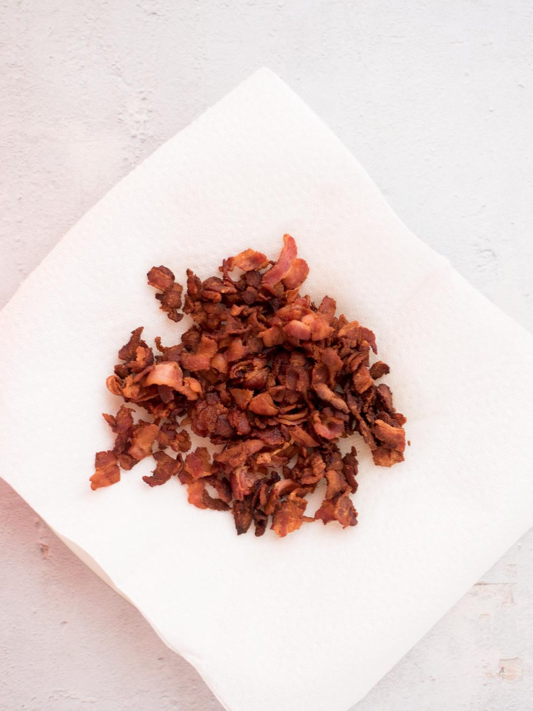 cooked bacon on a paper towel-lined plate