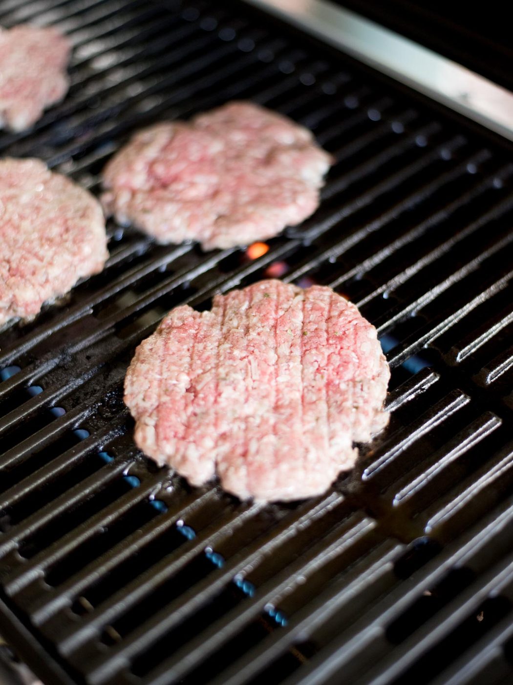 raw hamburger patties on the grill