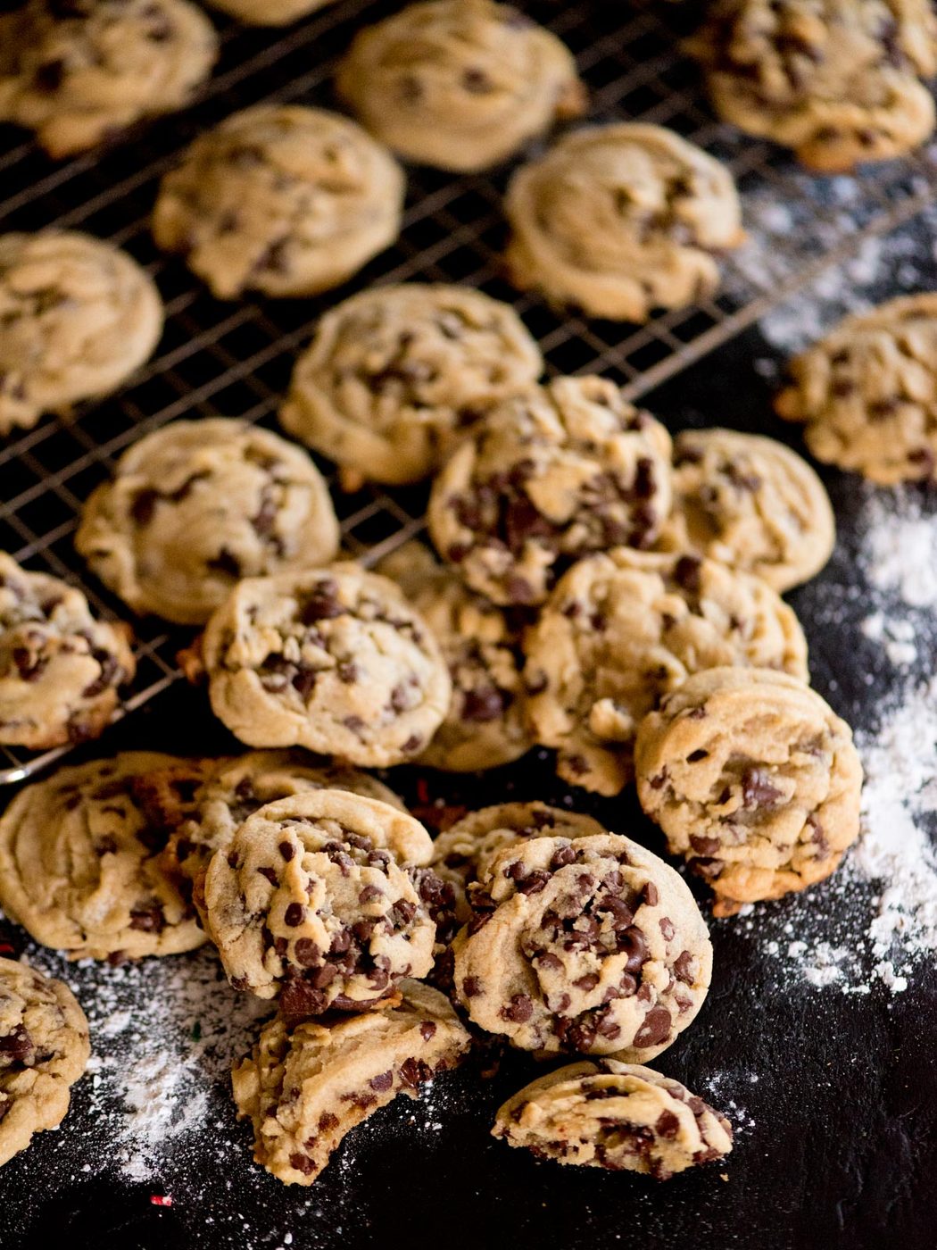 stack of a house favorite chewy chocolate chip cookies on a cooling rack with flour spread around