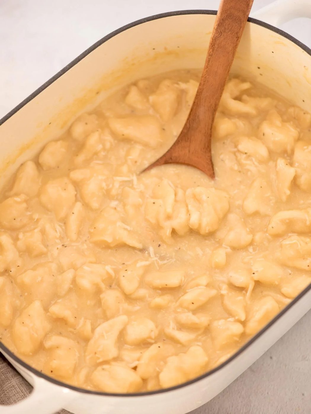 Ready to serve chicken and dumplings with canned biscuits with a serving spoon tucked in it.
