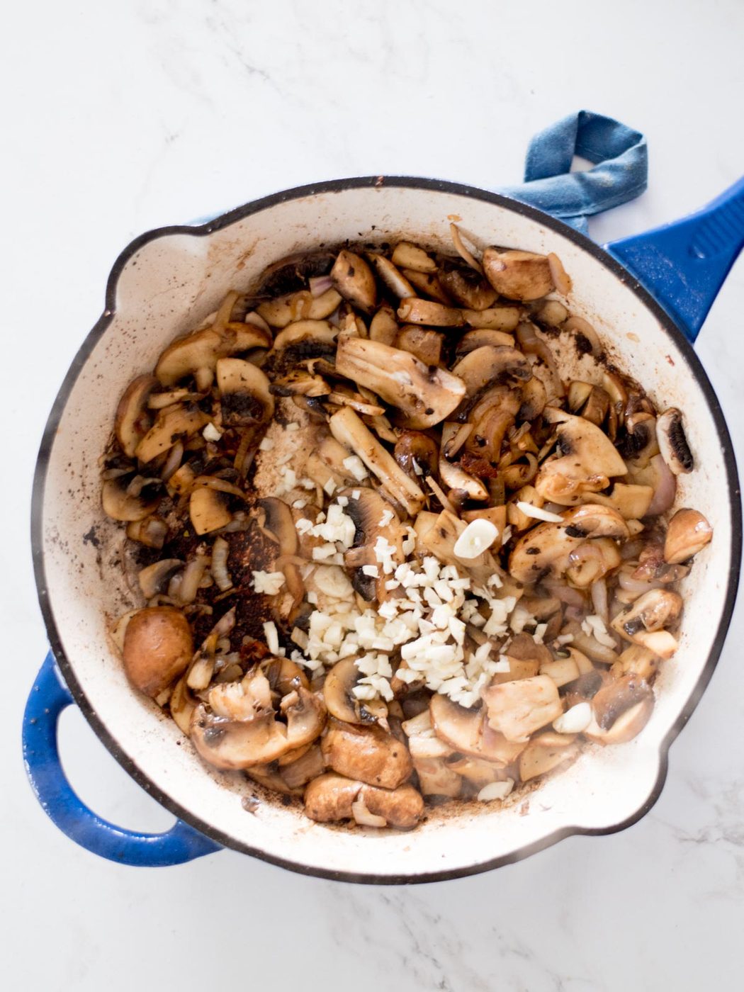 garlic added to sauteed mushrooms in a skillet