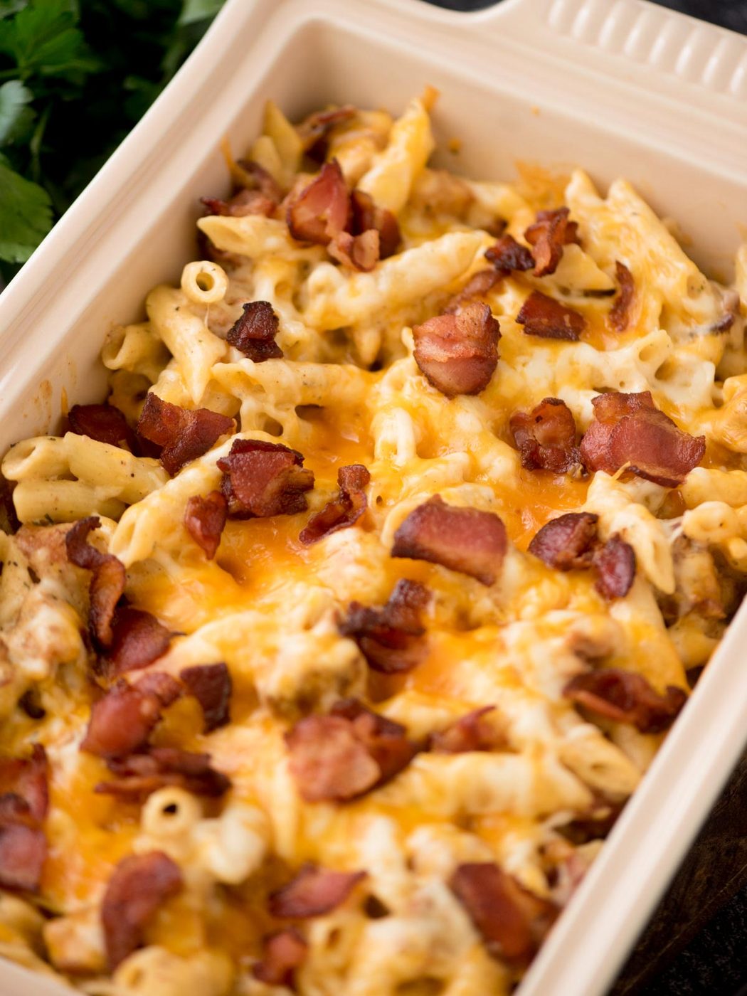 Chopped bacon pieces garnished over chicken bacon ranch pasta in a baking dish, ready to serve.