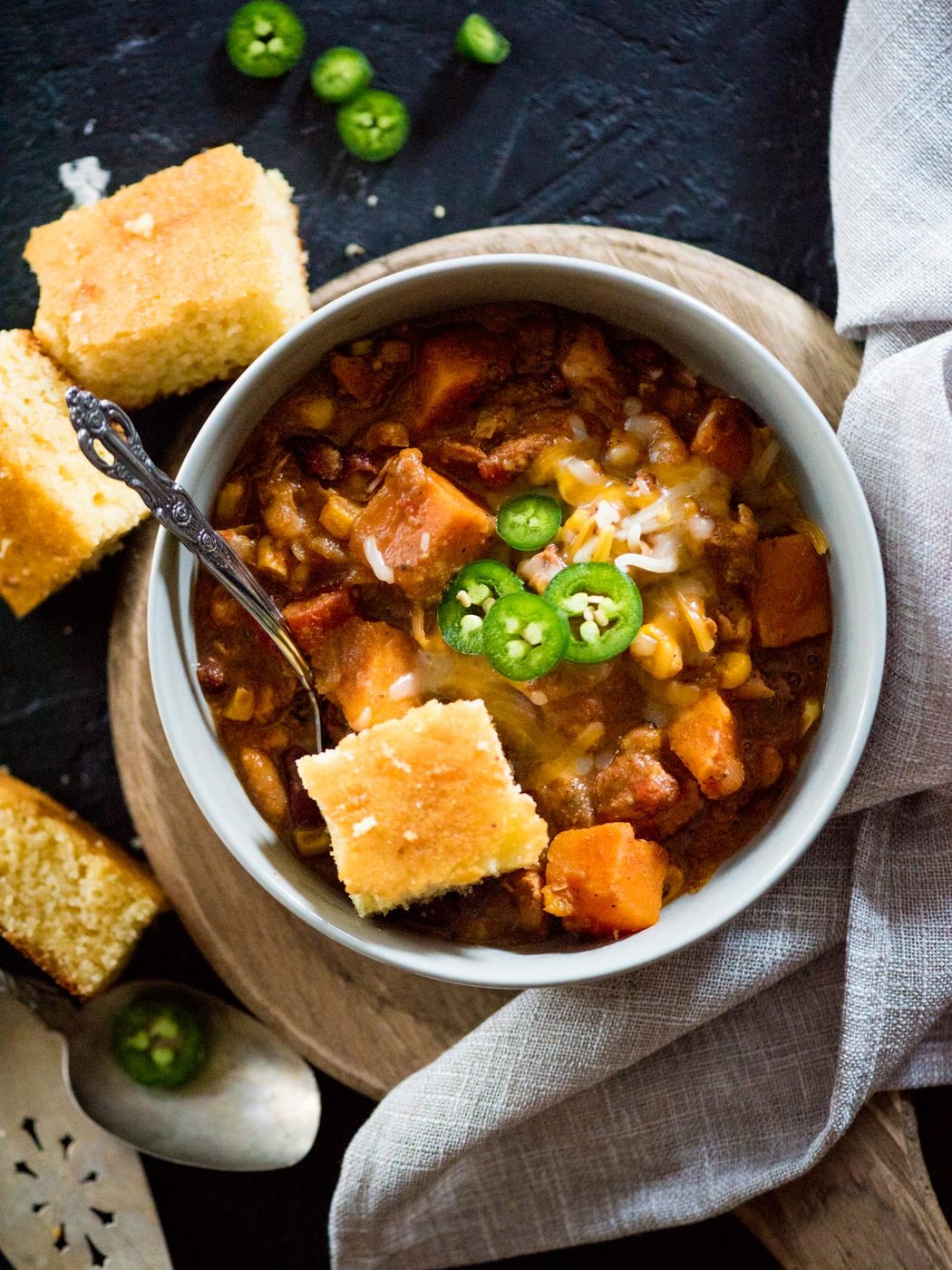 crockpot chicken chili in a bowl topped with cornbread and jalapenos