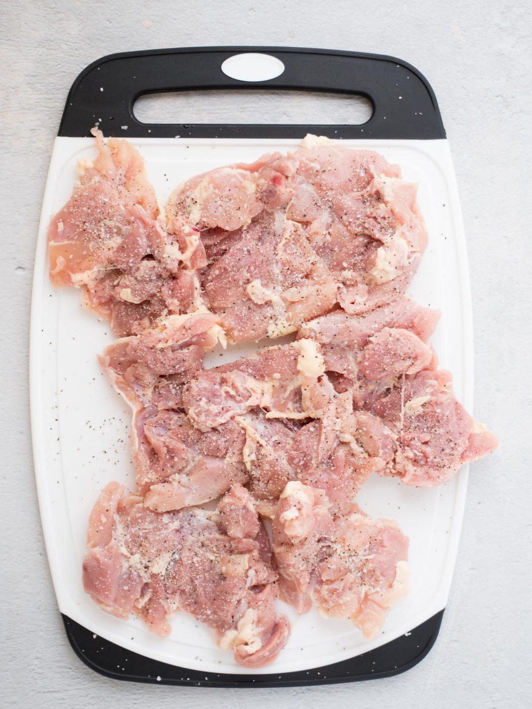 seasoned raw chicken thighs on a cutting board
