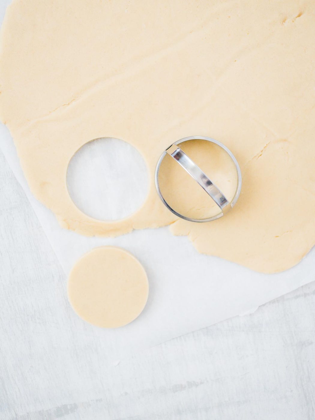 sugar cookie dough being cut out with a circle cookie cutter