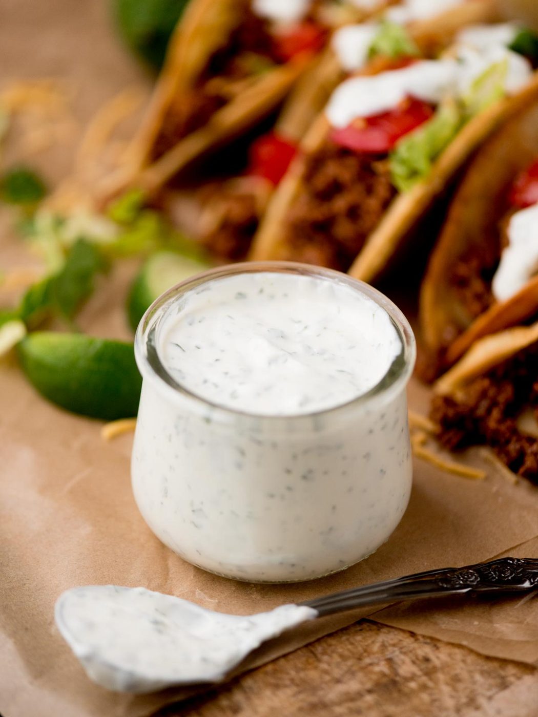 Small glass jar filled with cilantro lime sauce and a spoon covered in more laying next to it.
