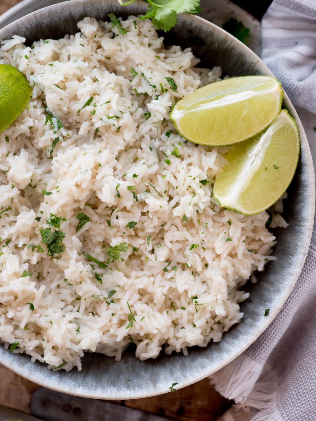 cilantro lime rice in a bowl topped with chopped cilantro and lime wedges