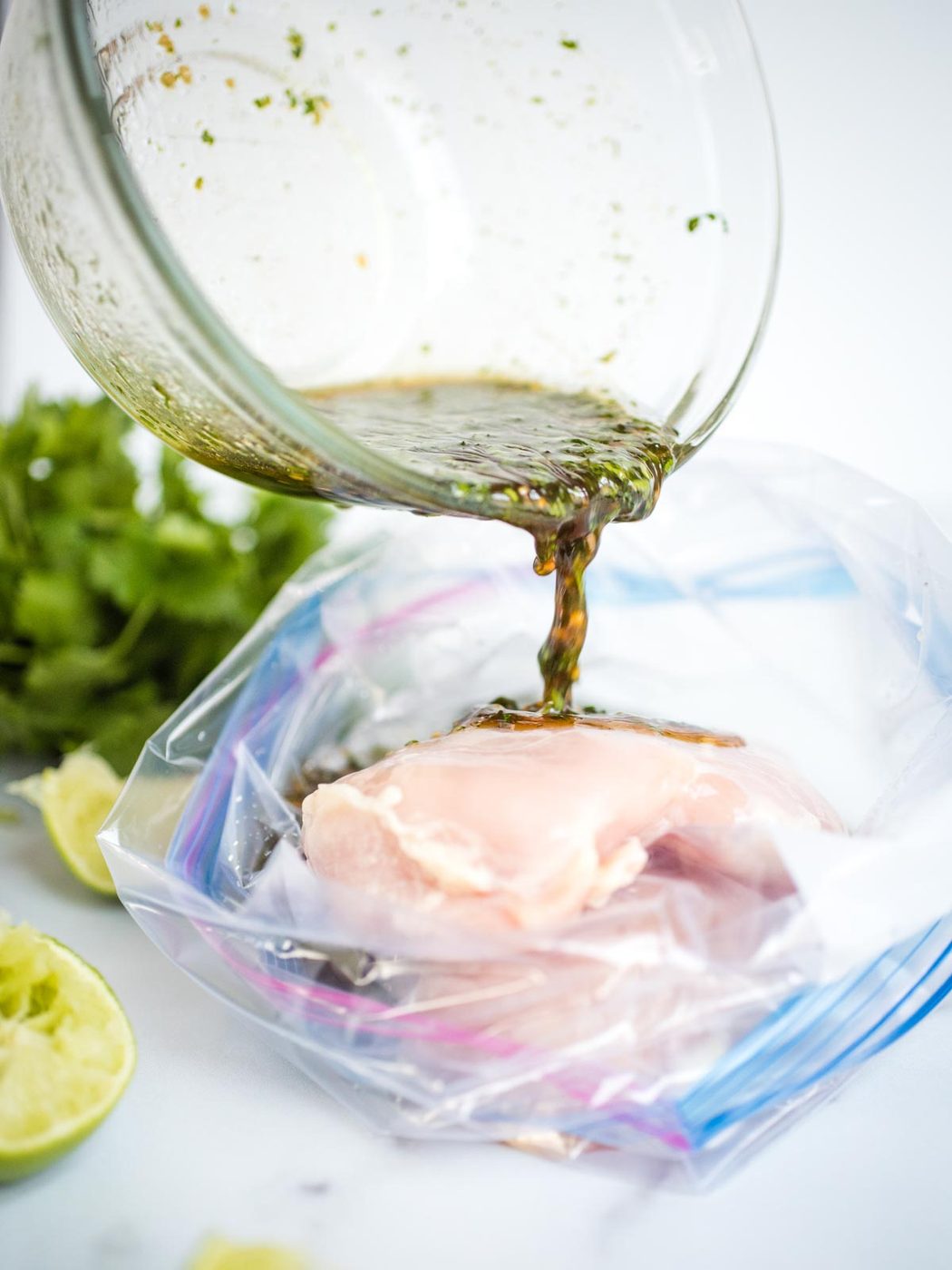 marinade being poured into bag of raw chicken