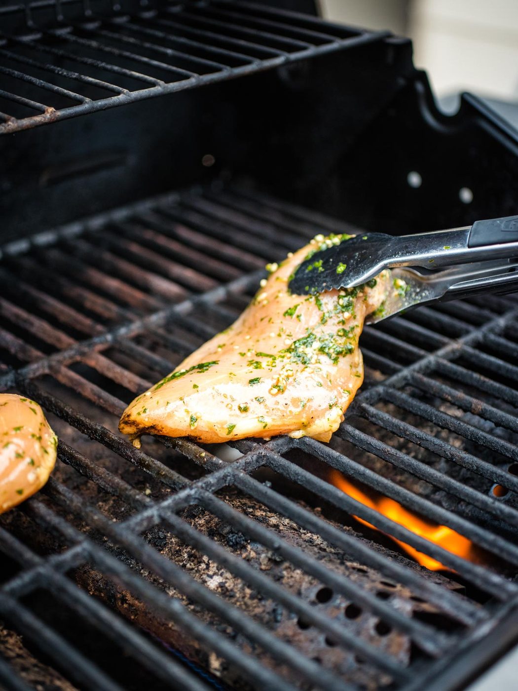 raw chicken being placed on grill