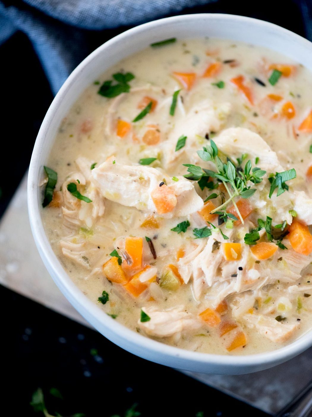 Creamy chicken and rice soup in a bowl topped with parsley and thyme