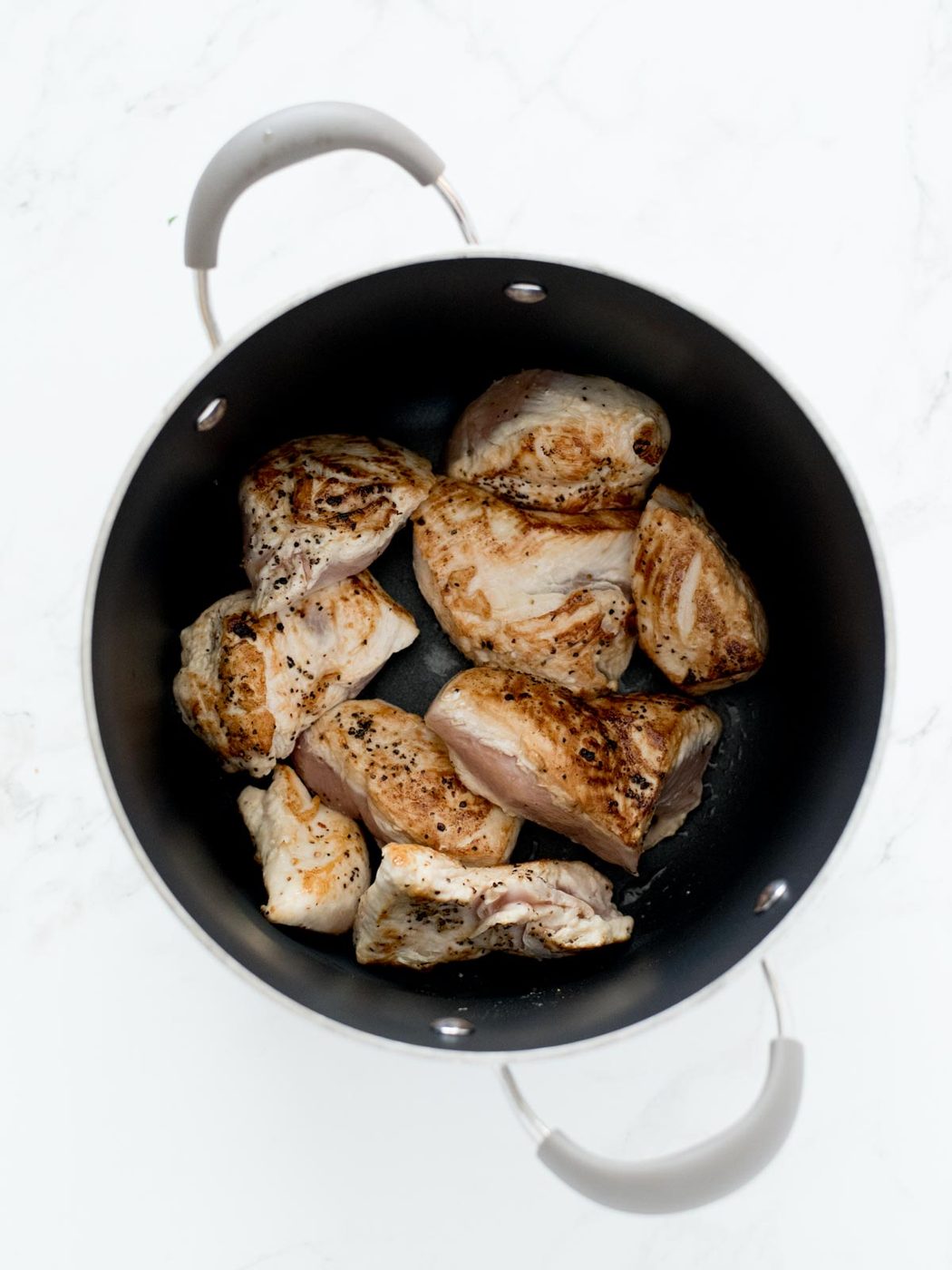 seared chicken in soup pot