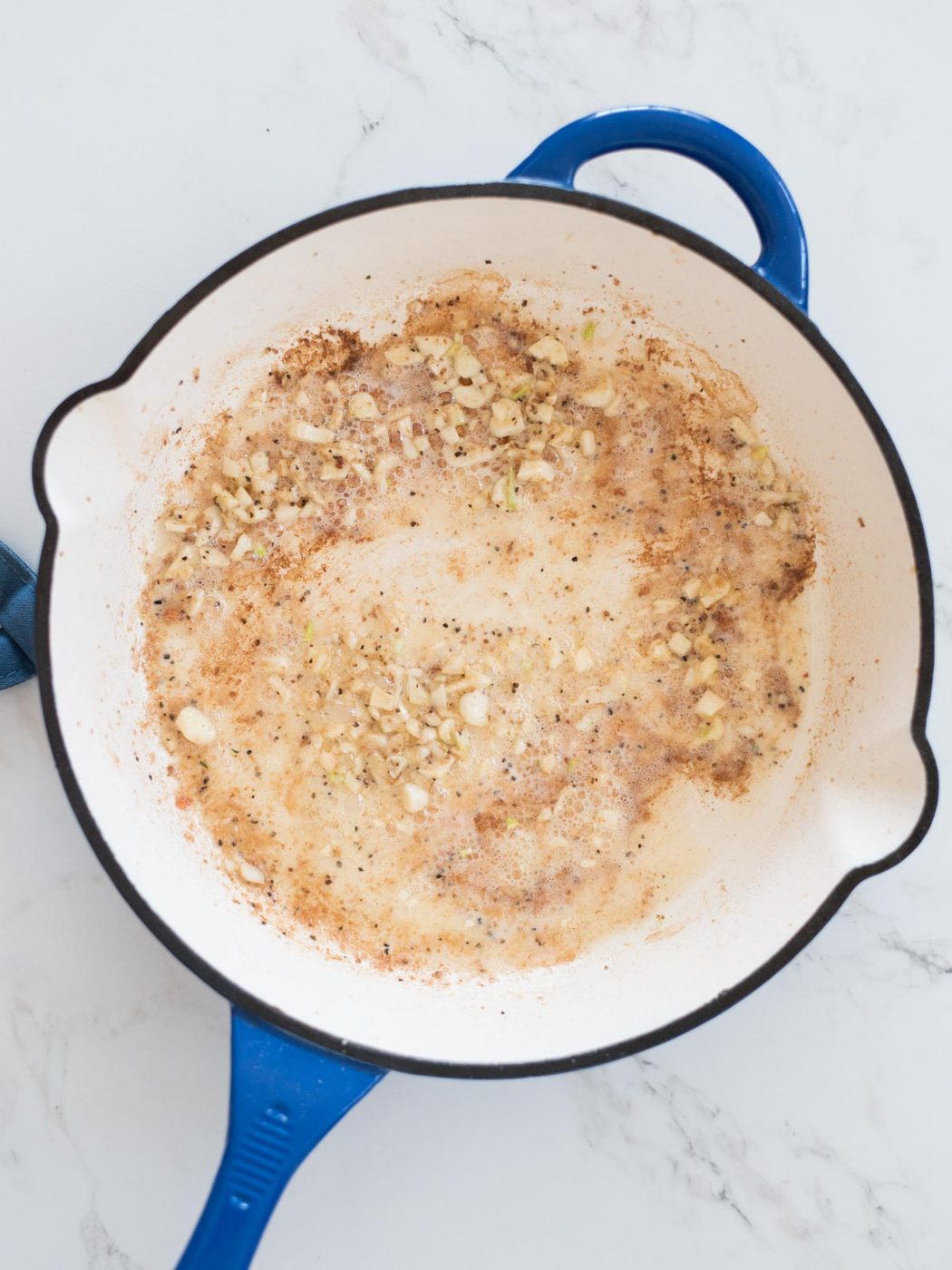 garlic being sauteed in an enameled cast iron skillet