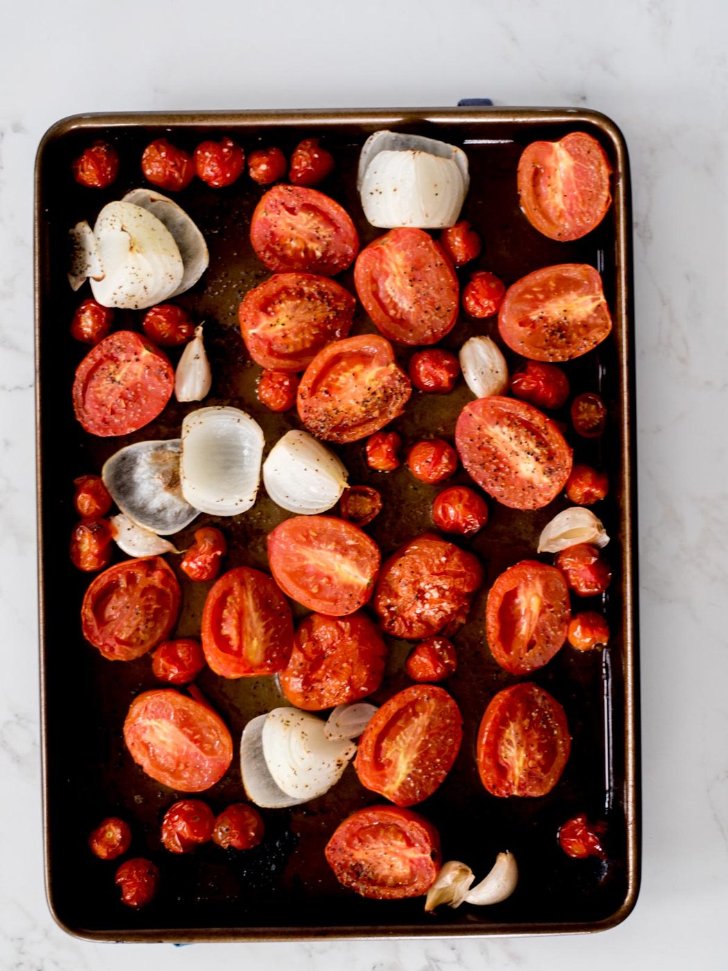 tomatoes, onion, and garlic that have been roasted on a sheet pan with olive oil, salt, and pepper