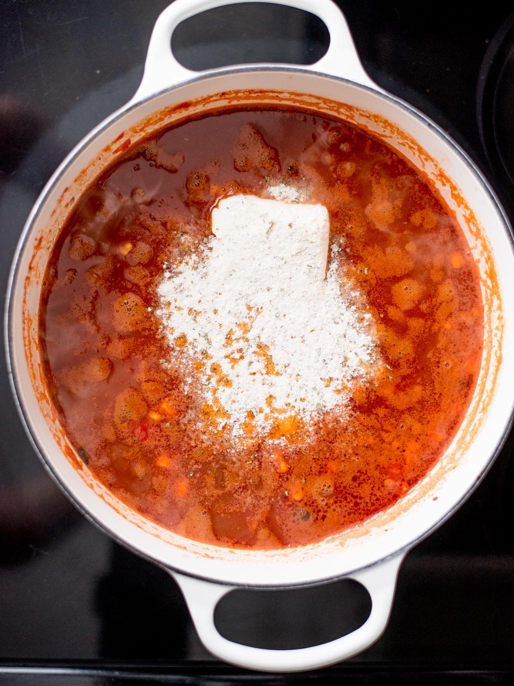 Dutch oven with cream cheese and dry ranch seasoning added to the tomato mixture.